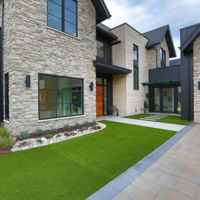 Close-up of the modern lakeside home’s front exterior, featuring clean lines, lush green grass, and thoughtful design details reflecting a retirement dream.