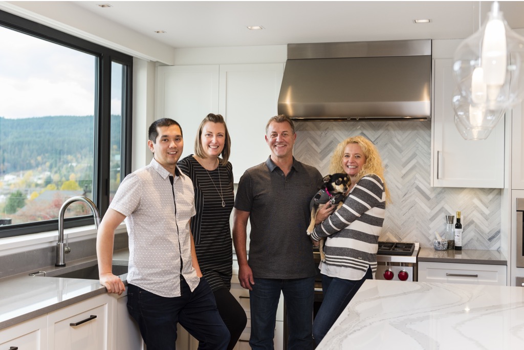Happy clients and designers stand in a freshly renovated kitchen.