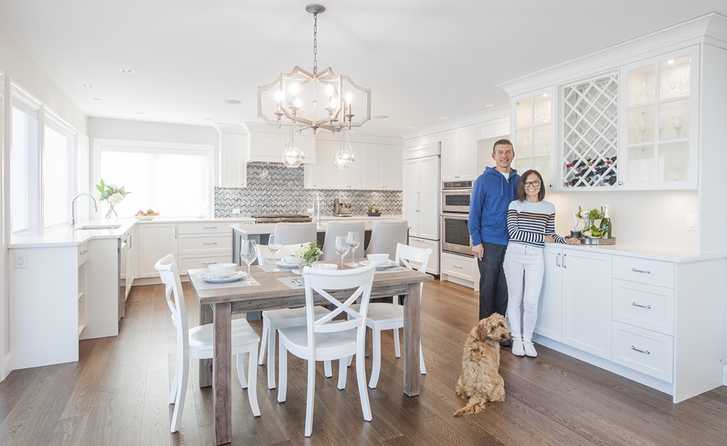A happy couple stands in their new bright kitchen.